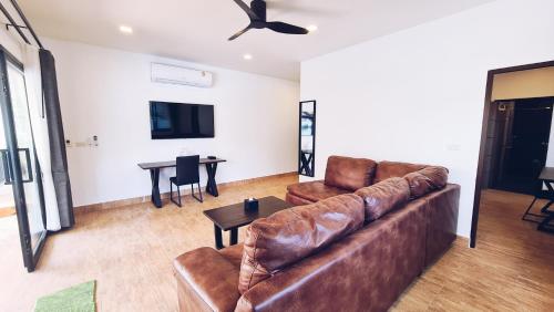 a living room with a leather couch and a table at Baan Rim Nam in Ko Chang