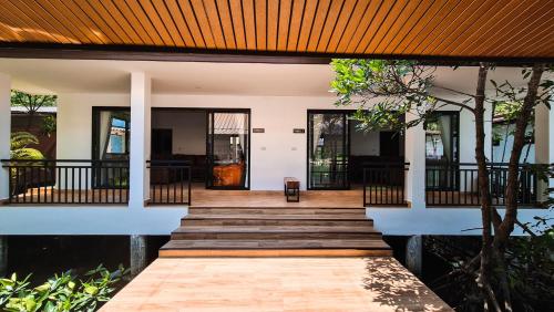 a home with a wooden walkway leading to the front door at Baan Rim Nam in Ko Chang