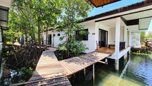a house with a wooden walkway next to a body of water at Baan Rim Nam in Ko Chang