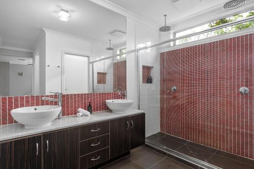 a bathroom with two sinks and a red tiled wall at Luxury Coastal Escape in Tootgarook
