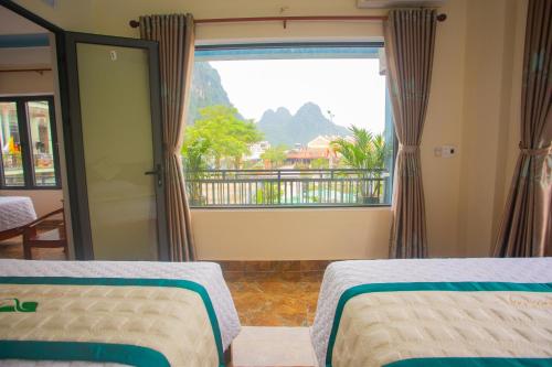 a bedroom with two beds and a large window at Phong Nha Green Homestay in Phong Nha