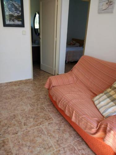 a bed with an orange comforter in a room at Casa Rural Masia d'en Gall in L'Aldea