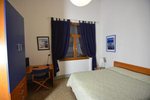a bedroom with a bed and a desk and a window at Albergo Casa Al Sole in Greve in Chianti