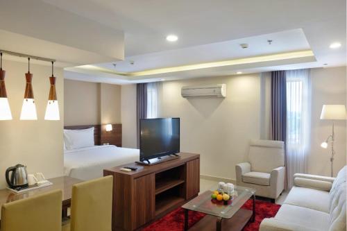 a hotel room with a bed and a flat screen tv at Next Hotel Yogyakarta in Yogyakarta
