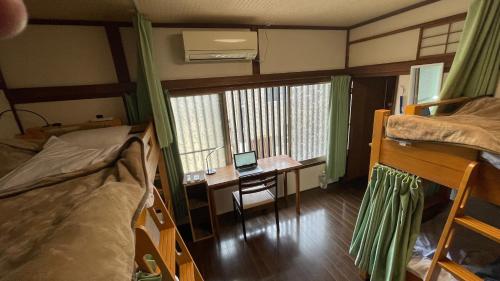 a dorm room with a desk and a laptop on a table at Guesthouse KYOTO COMPASS in Kyoto