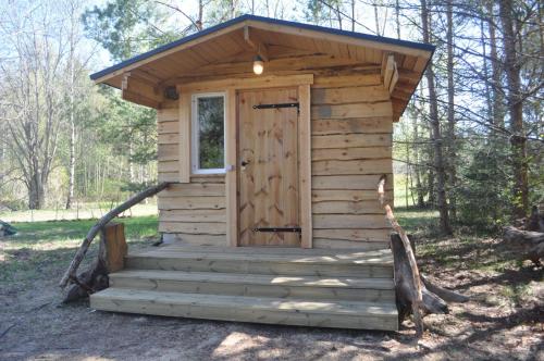 a wooden outhouse with a door in the woods at Korjuse Moori metsaonn- forest hut in Korjuse