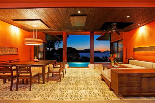 a dining room with a table and a couch at Sri Panwa Phuket Luxury Pool Villa Hotel - SHA Plus in Panwa Beach