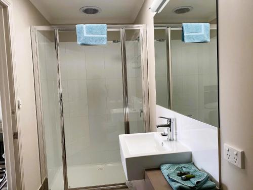 a bathroom with a sink and a shower with blue towels at Dalvue Motel in Terang
