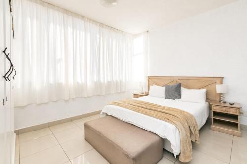 a white bedroom with a bed and a window at Inn & Out Sandton Park in Johannesburg