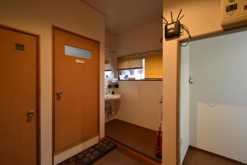 a small bathroom with a door and a sink at Guest House Iwato in Takachiho