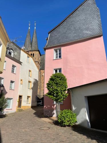 un gruppo di edifici con un albero in una strada di Uriges Ferienhaus in der Altstadt von Saarburg mit Sauna, Kinderspielecke, 1000Mbit Wlan, 1 Minute vom Wasserfall entfernt a Saarburg