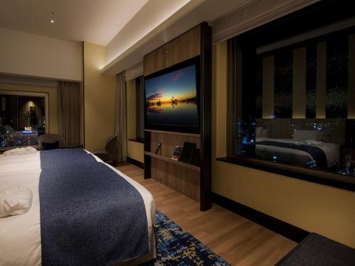 a hotel room with a bed and a large window at Hotel Monterey Edelhof Sapporo in Sapporo