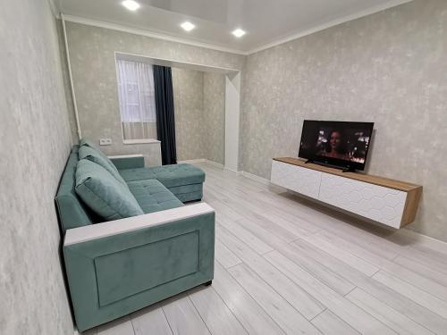 sala de estar con sofá verde y TV en Чистая уютная квартира! Рядом сквер,море, en Aktau