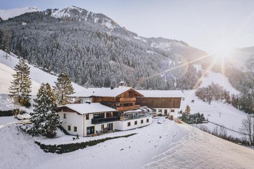 a house on a snow covered mountain with the sun shining at Panorama Hotel Guggenbichl - inkl Sommerkarte, einmaliger Eintritt ins Tauern Spa & bester Ausblick über Kaprun in Kaprun