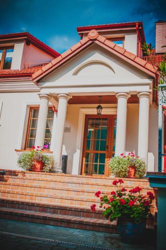 a white house with flowers on the stairs at Pod Kolumnami in Pilica