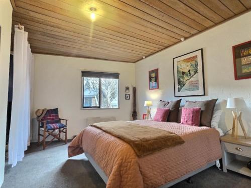 a bedroom with a large bed with a wooden ceiling at Snow Gums Apartment 4, alpine-getaways in Dinner Plain