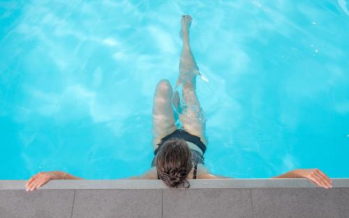 een vrouw drijvend in een zwembad bij Nicey - Hôtel Spa, Lounge, Coworking in Romilly-sur-Seine
