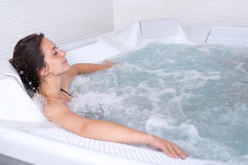 una mujer está sentada en una bañera en Nicey - Hôtel Spa, Lounge, Coworking en Romilly-sur-Seine