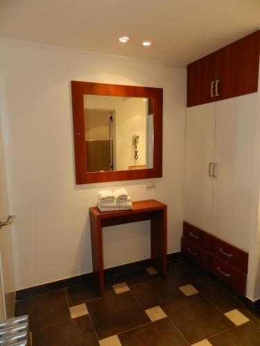 a bathroom with a mirror and a wooden table at Hotel A&B Internacional in Buenos Aires
