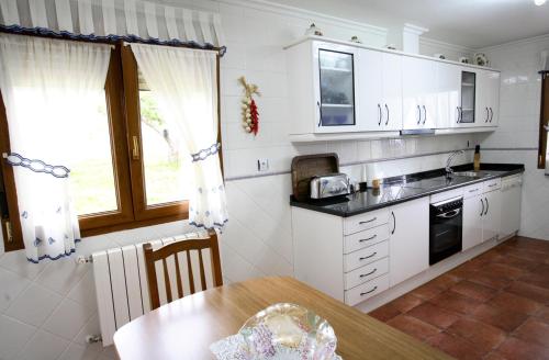 cocina con armarios blancos y mesa de madera en Vivienda Vacacional Supereda, en San Juan de Parres