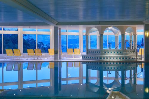 a swimming pool with chairs and a table in a building at Panorama Boutique Apartment with complimentary Spa access at Solbad Hotel in Sigriswil