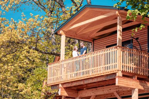 a man and woman standing on the balcony of a tree house at Chalets & Glamping Nassfeld by ALPS RESORTS in Kötschach