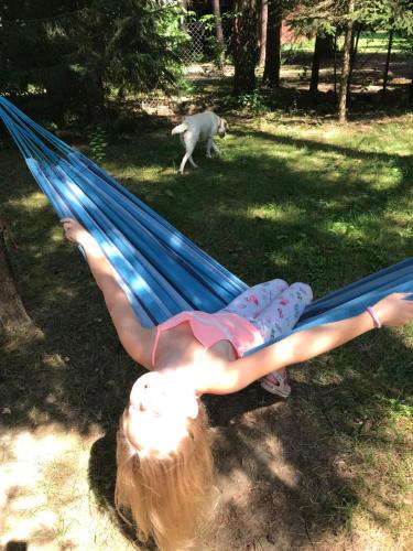 a girl laying in a hammock with a dog at Modrzewiowy Dworek in Zyzdrojowa Wola