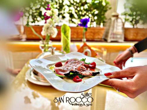 a person holding a plate of food on a table at Suite San Rocco Wellness&Spa in Ruvo di Puglia