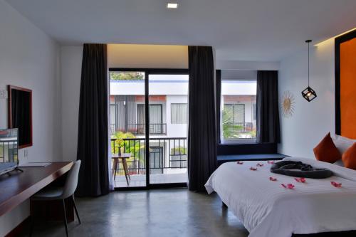 a bedroom with a bed and a desk and windows at Central Corner Suite in Siem Reap