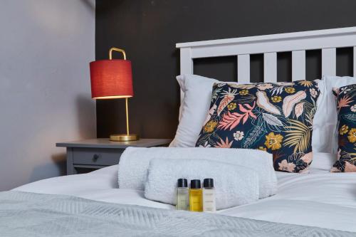 a bedroom with a white bed with a red lamp at Delven House- Serviced Apartments in Castle Donington