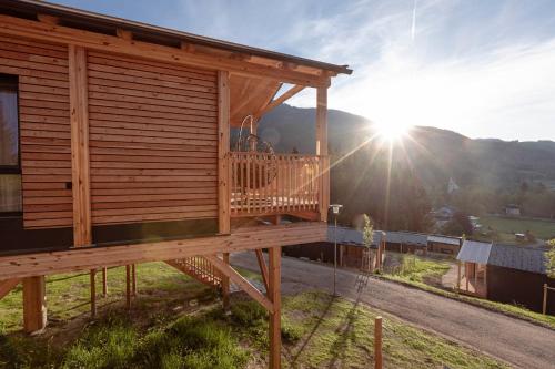 a house with a deck with the sun in the background at Chalets & Glamping Nassfeld by ALPS RESORTS in Kötschach