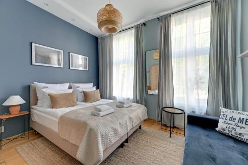 een slaapkamer met een bed met blauwe muren en ramen bij Downtown Apartments Old Town Ogarna IV in Gdańsk