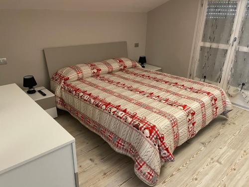- une chambre avec un lit et une couette rouge et blanche dans l'établissement Appartements Chez Maghy, à Aoste