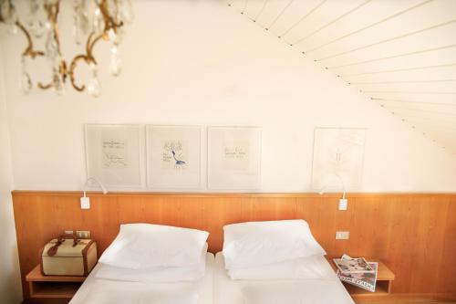 two beds in a room with certificates on the wall at Weisses Rössl in Caldaro
