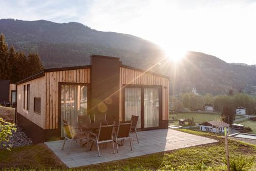 a small house with a table and chairs on a patio at Chalets & Glamping Nassfeld by ALPS RESORTS in Kötschach