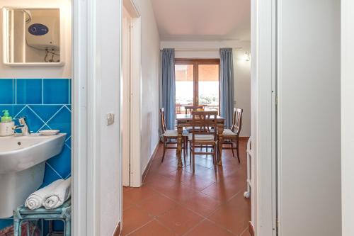 a bathroom with a sink and a table with chairs at Erica Piano Terra & Erica Primo Piano in Golfo Aranci