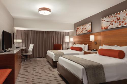 a hotel room with two beds and a flat screen tv at Radisson Hotel & Conference Centre Calgary Airport in Calgary