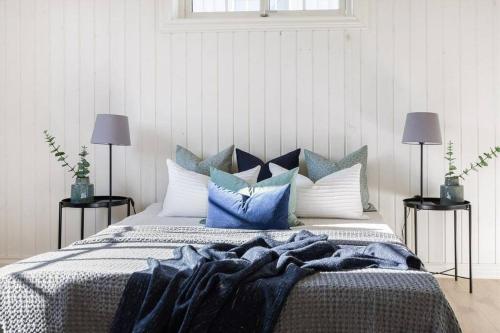 a bedroom with a bed with blue and white pillows at Lys og sentral leilighet med terrasse og hage in Lillehammer