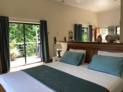 a bedroom with a bed with blue pillows and a window at Rock and Palm Lodge Self catering appartment in Baie Lazare Mahé