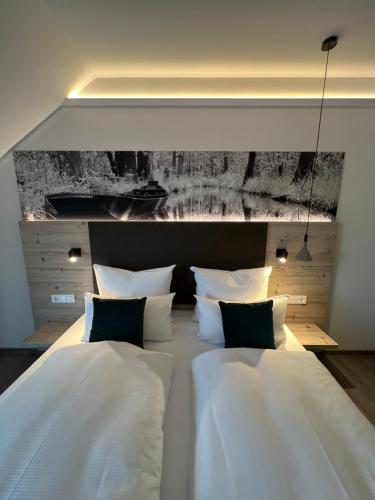 a large bed with white sheets and black pillows at Landhotel Burg im Spreewald - Resort & Spa in Burg