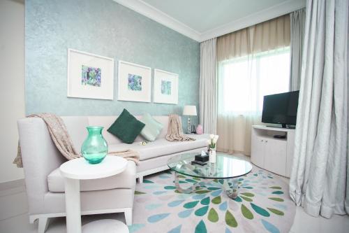 a living room with a white couch and a tv at OSKENA Vacation Homes - Damac Maison Dubai Mall Street in Dubai