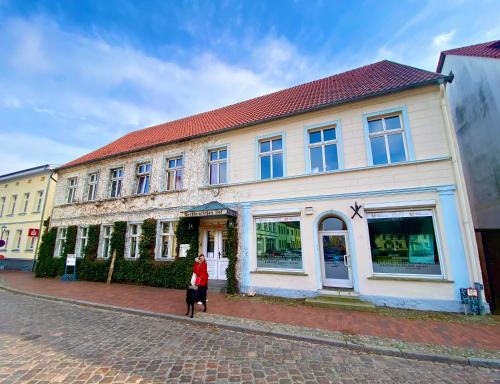 a woman walking in front of a building at norddeutscher Hof - Kutscherstation in Usedom Town