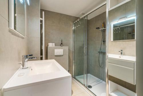 een badkamer met een wastafel en een glazen douche bij Retro woning te centrum Oostende, 5min van de kust in Oostende
