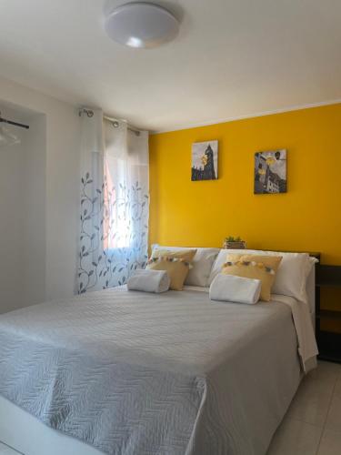1 dormitorio con 1 cama blanca grande y paredes amarillas en LAGUNA BLU Camera SOLE con terrazza panoramica in comune, en Chioggia