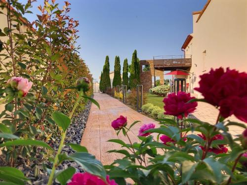 un jardín con flores rosas y una pasarela de ladrillo en Gîtes La Catalane en Théza