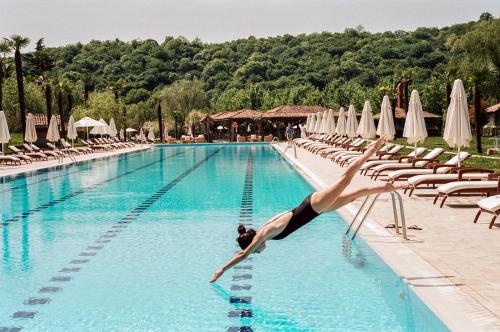 a woman diving into a swimming pool at a hotel at Lopota Lake Resort & Spa in Napareuli