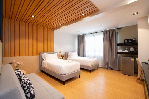 una habitación de hotel con dos camas y un sofá en โรงแรมอินฟินิทเกษตร, en Ban Yang
