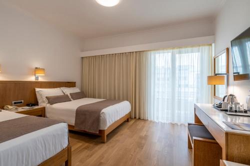 a hotel room with two beds and a window at Kydon The Heart City Hotel in Chania Town