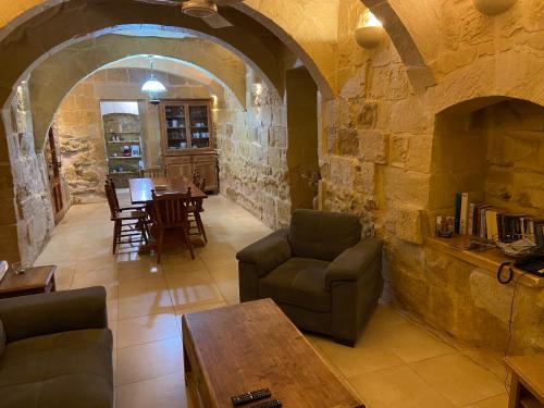 a living room with a table and chairs and a stone wall at Farmhouse Razzett Cora in Victoria