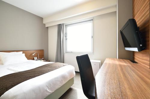 um quarto de hotel com uma cama e uma televisão de ecrã plano em Kichijoji Tokyu REI Hotel em Musashino